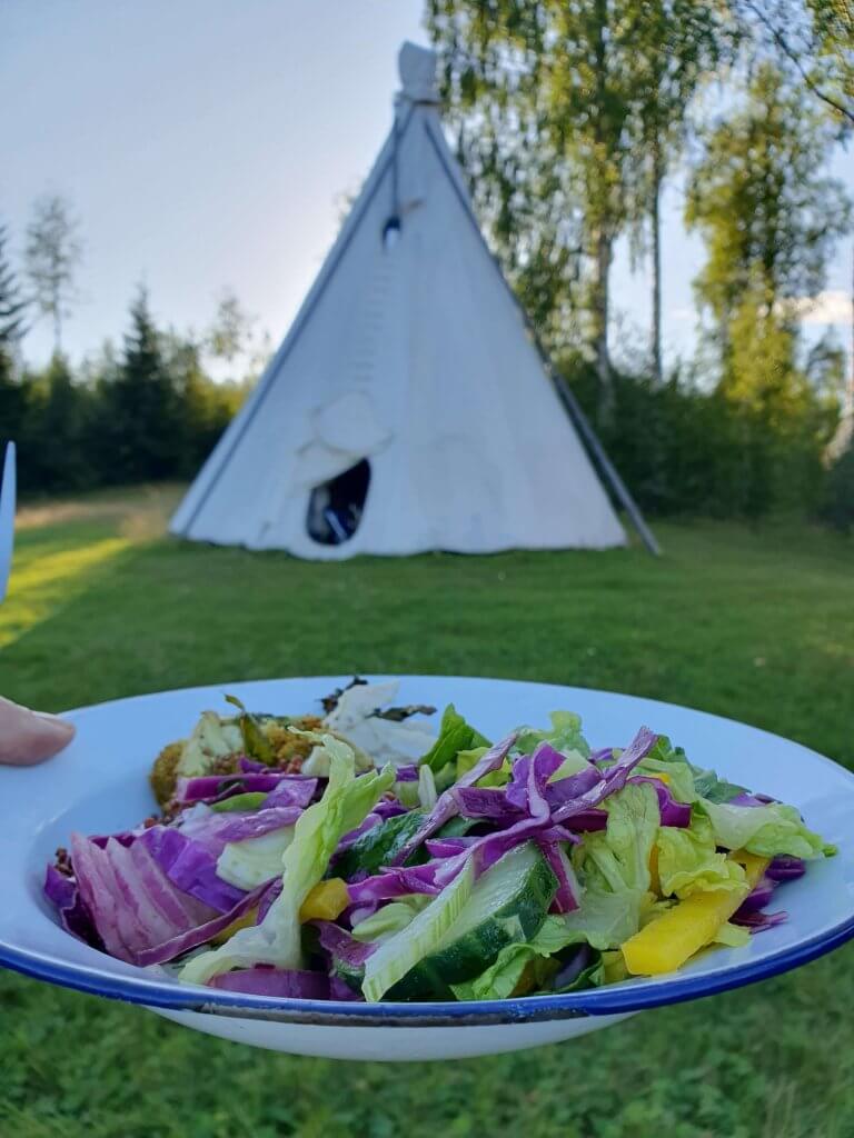 A healthy salad with a Tipi in the background at the Women's Retreat